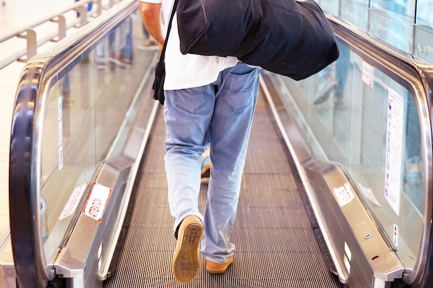 Foto ein mann mit gepäck auf einer horizontalen rolltreppe