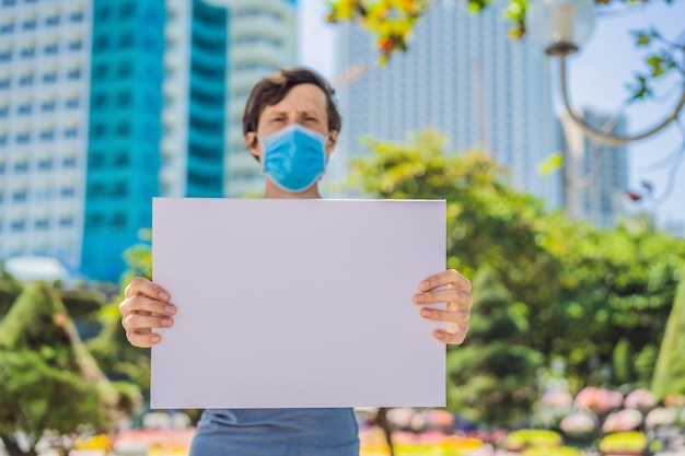 Ein Mann mit medizinischer Maske beugt einer Coronavirus-Erkrankung vor und hält ein Plakat für kostenlose Aufschriften