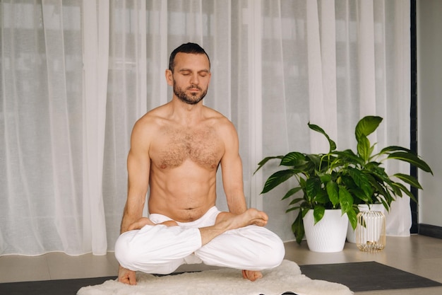 Ein Mann mit nacktem Oberkörper macht Yoga in einem Fitnessraum das Konzept eines gesunden Lebensstils