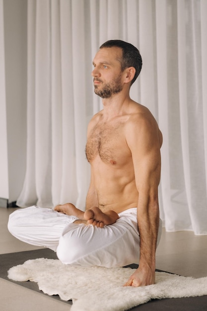 Ein Mann mit nacktem Oberkörper macht Yoga in einem Fitnessraum das Konzept eines gesunden Lebensstils