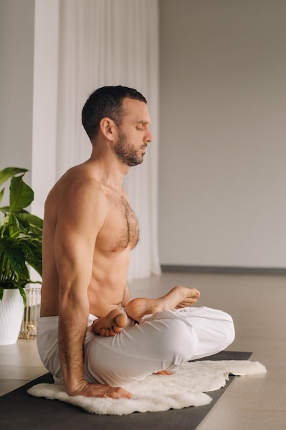 Ein Mann mit nacktem Oberkörper macht Yoga in einem Fitnessraum das Konzept eines gesunden Lebensstils