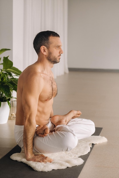 Ein Mann mit nacktem Oberkörper macht Yoga in einem Fitnessraum das Konzept eines gesunden Lebensstils