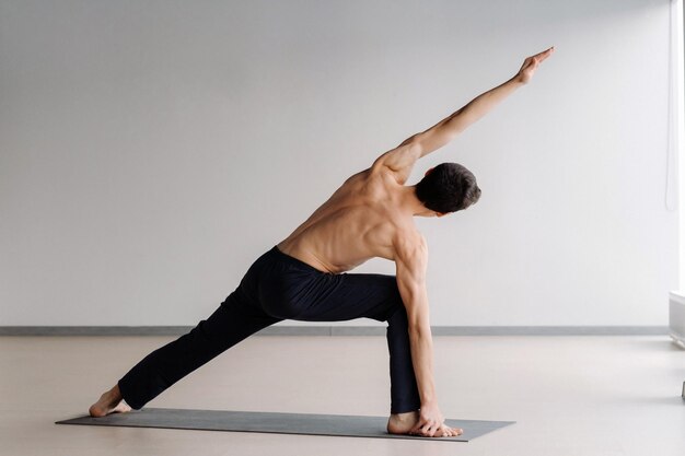 Ein Mann mit nacktem Oberkörper trainiert im Stehen und macht Dehnübungen im Fitnessstudio.