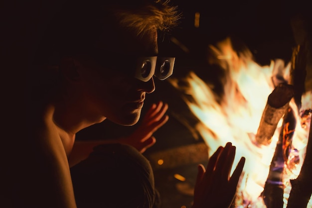Foto ein mann mit schutzbrille bei einem lagerfeuer in der nacht