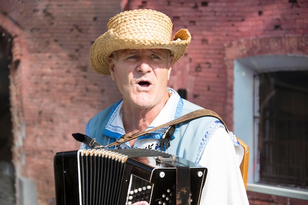 Ein Mann mit Strohhut, der Mundharmonika spieltHarmonist