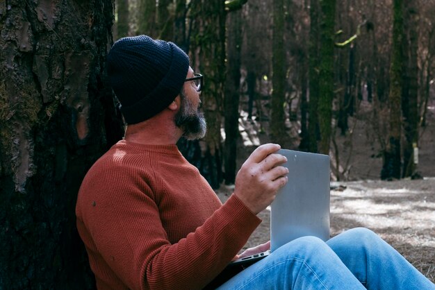 Ein Mann nutzt Technologie-Verbindung im Naturpark Wald Wälder Fernarbeiter kleine Reise-Geschäft Lebensstil Menschen Arbeiten in der Natur alternatives Büro Kleinunternehmen Reisende Arbeitsleben