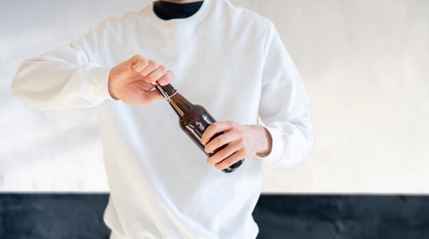Ein Mann öffnet die Glasbierflasche auf Party, schlechte Angewohnheit, Alkoholsüchtiger