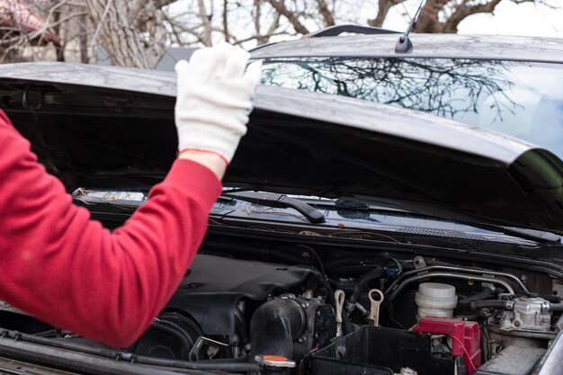 Ein Mann öffnet die Motorhaube eines Autos für Reparaturen Autoreparatur und -wartung