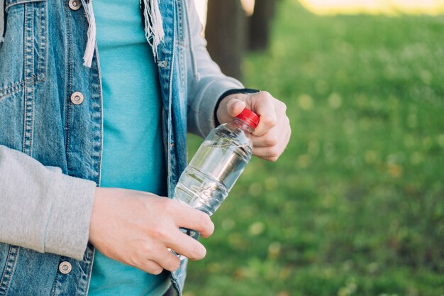 Ein Mann öffnet eine Plastikflasche mit Mineralwasser