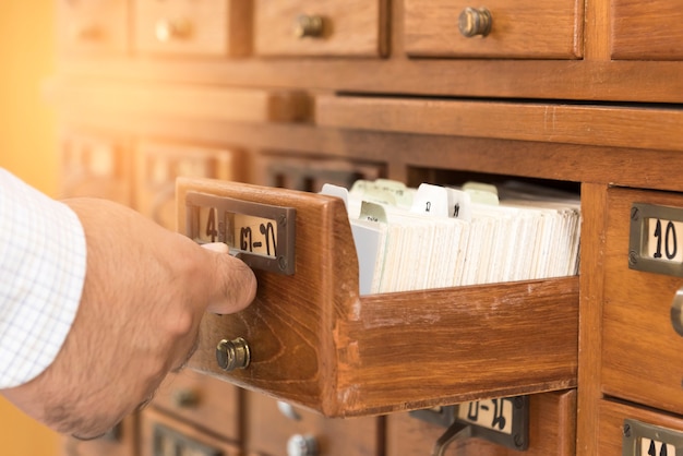 Ein Mann öffnet Holzschrank gespeichert Bibliothek Index.