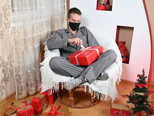 Ein Mann packt ein Geschenk in einer Maske aus. Foto in hoher Qualität