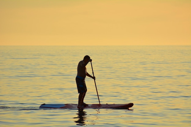 Foto ein mann paddleboardet auf dem meer bei sonnenuntergang