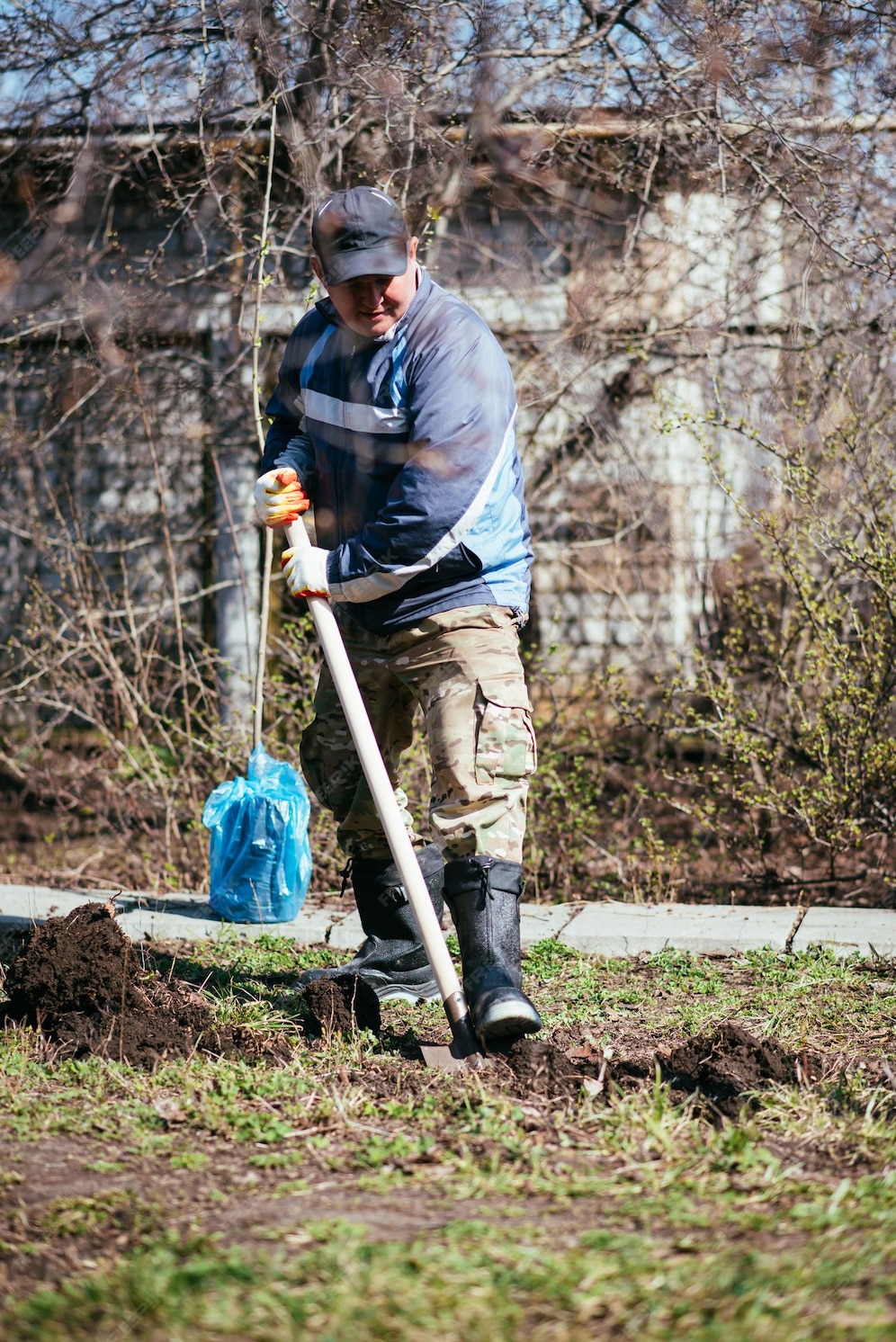 Ein Mann pflanzt einen jungen Baum Der Bauer gräbt den Boden mit einer