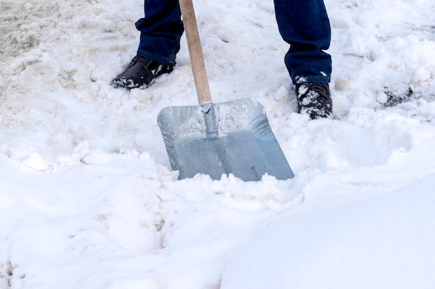 Ein Mann reinigt Schnee mit einer Metallschaufel