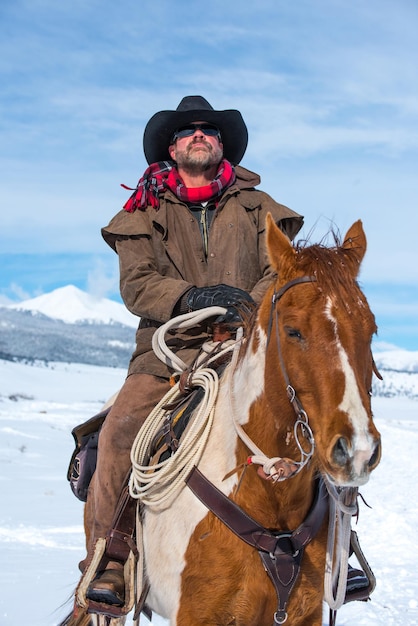 Ein Mann reitet auf einem Pferd im Schnee gegen den Himmel