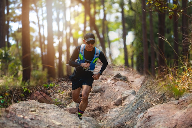 Ein Mann Runner of Trail. und Sportlerfüße mit Sportschuhen für Trailrunning im Wald