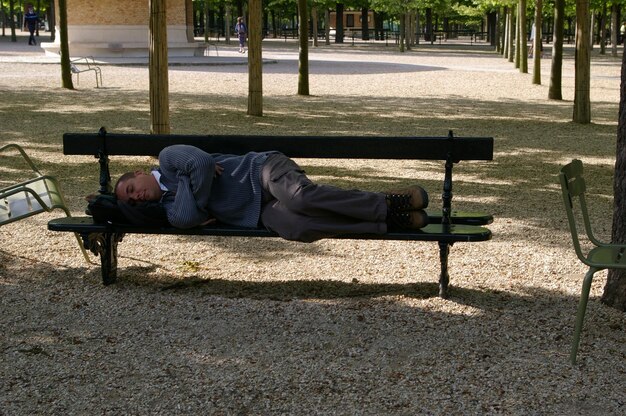 Foto ein mann schläft auf einer bank im park