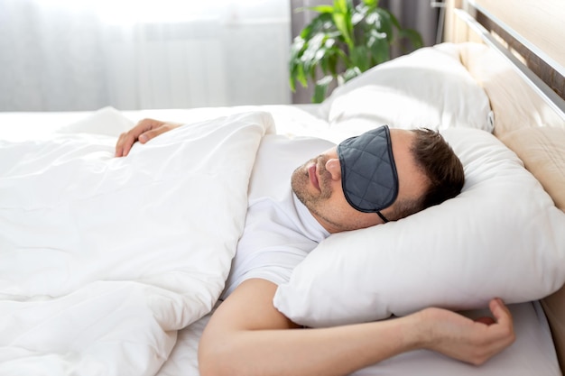 Ein Mann schläft in einem Bett mit einer Maske vor den Augen