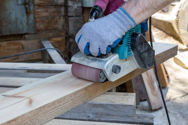 Ein Mann schleift Holzbretter mit einer Schleifmaschine Holzarbeiten Zimmerei Hobby