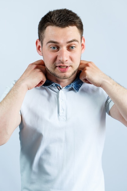 Ein Mann schließt einen Knopf an seinem weißen Polo