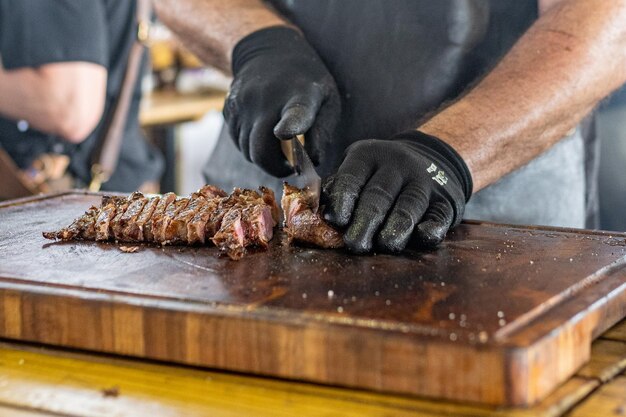 Foto ein mann schneidet fleisch auf einem holztisch