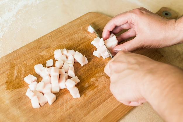 Ein Mann schneidet rohes Schweinefett in Stücke