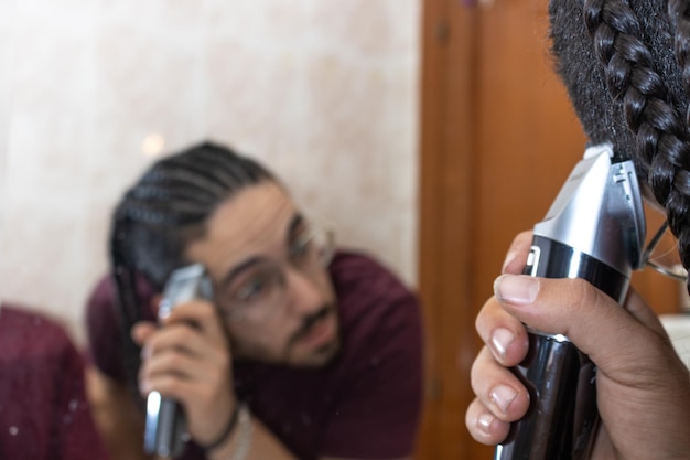 Ein Mann schneidet sich im Badezimmer mit einer Haarschneidemaschine die Haare Nahaufnahme eines Mannes, der sich im Badezimmer die Haare mit einer Haarschneidemaschine schneidet