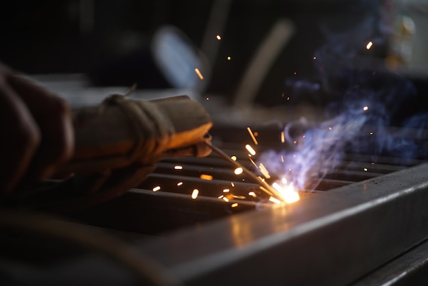 Foto ein mann schweißt ein stück metall mit funken