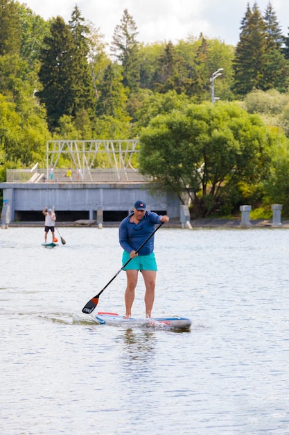 Ein Mann schwimmt auf einem Surfbrett und schiebt mit einem Ruder Paddleboarding ab