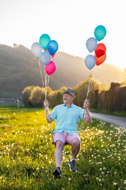 Ein Mann schwingt auf einer Schaukel in Luftballons