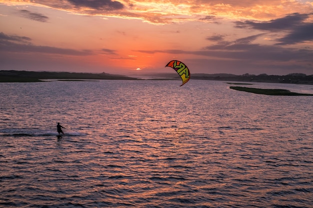 Ein Mann segelt bei Sonnenuntergang mit seinem Kiteboard über die Lagune von Garzon Maldonado Uruguay