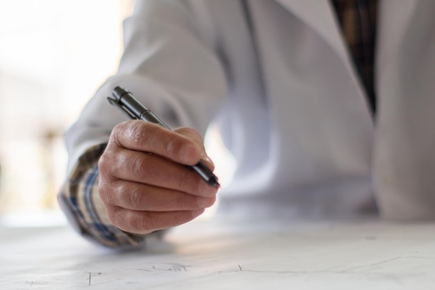 Ein Mann sitzt an einem Schreibtisch, hält einen Stift in der Hand und zeichnet eine Karte.