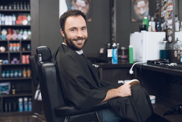 Ein mann sitzt auf dem friseurstuhl im friseursalon des mannes