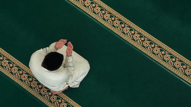 Ein Mann sitzt auf einem Gebetsteppich in einer Moschee.