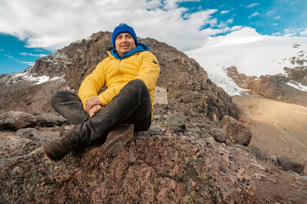 Ein Mann sitzt auf einem Stein auf einem Berg