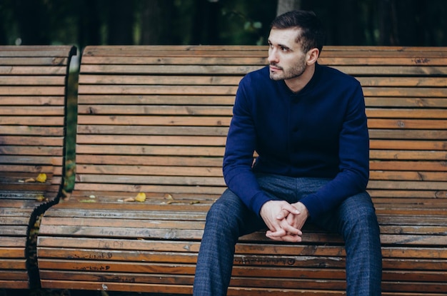 Ein Mann sitzt auf einer Bank im Park