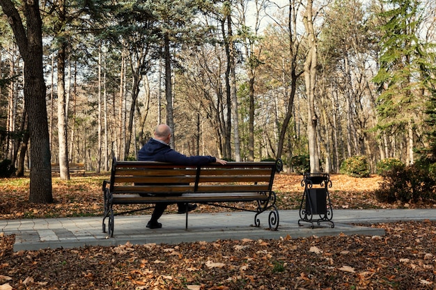 Ein Mann sitzt auf einer Bank in einem Herbstpark. Einsamkeit und Traurigkeit. Rückansicht.