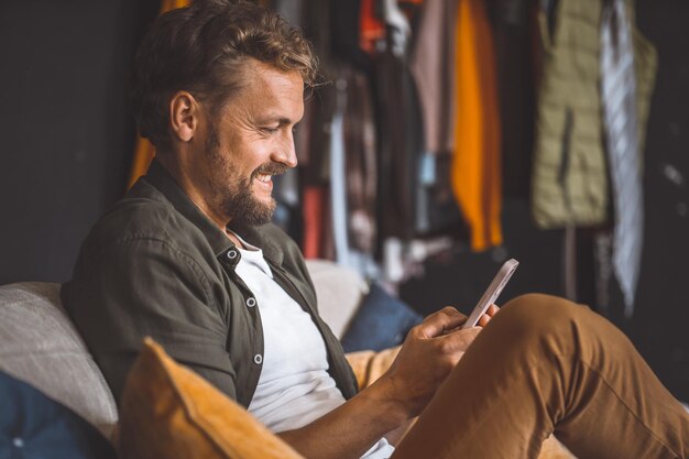 Foto ein mann sitzt auf einer couch und beschäftigt sich mit seinem handy