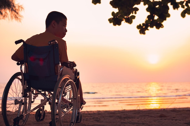 Ein Mann sitzt bei Sonnenuntergang am Strand gegen den Himmel