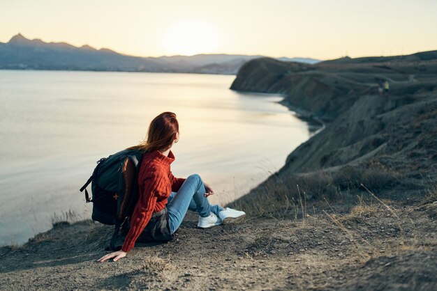 Foto ein mann sitzt bei sonnenuntergang auf einem felsen am meer gegen den himmel