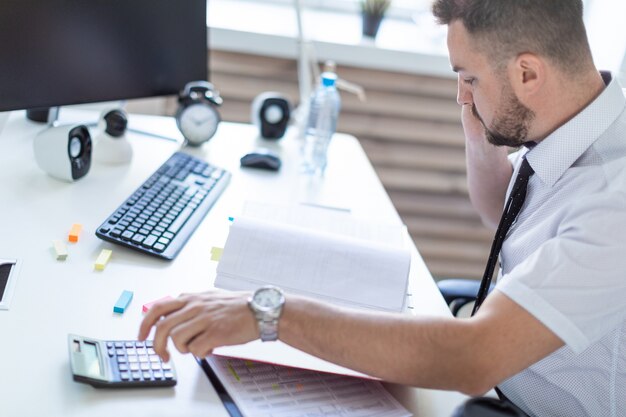 Ein Mann sitzt im Büro, arbeitet mit Dokumenten und telefoniert.