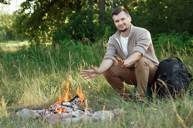 Ein Mann sitzt im Freien am Feuer.