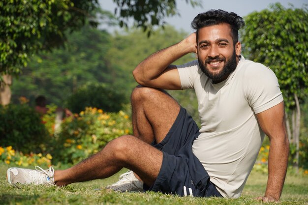 Ein Mann sitzt im Park und posiert in Freizeitkleidung