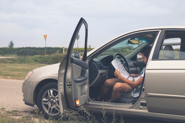 Ein Mann sitzt in einem Auto und schaut auf eine Karte der Gegend.