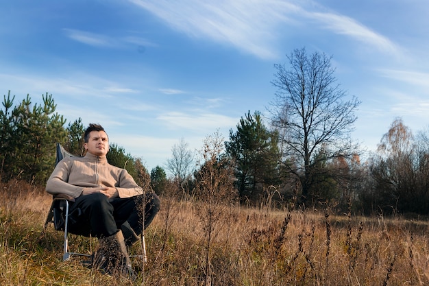 Ein Mann sitzt in einem Schaukelstuhl in der Natur