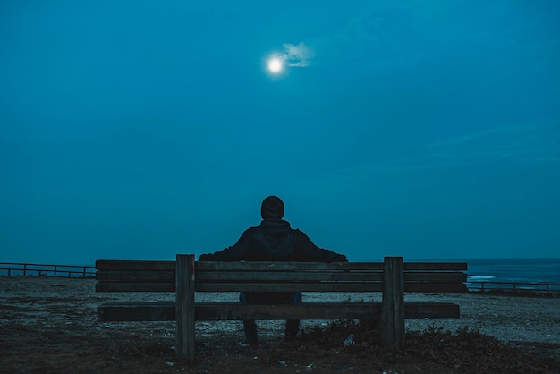 Ein Mann sitzt nachts auf einer Bank