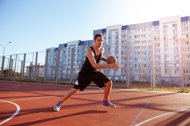 Ein Mann spielt Basketball auf dem Bezirks-Sportplatz gegen Wohngebäude.