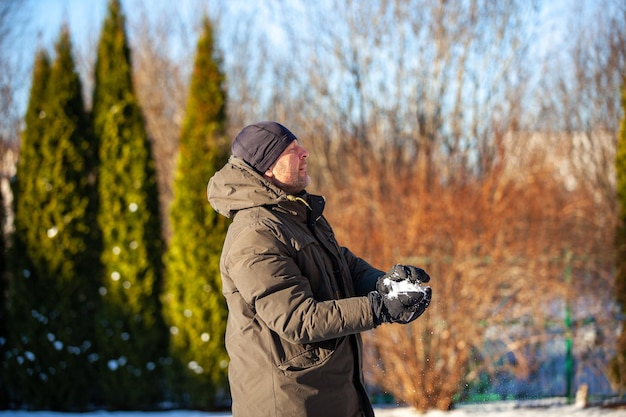 Ein Mann spielt Schneebälle im Hof des Hauses