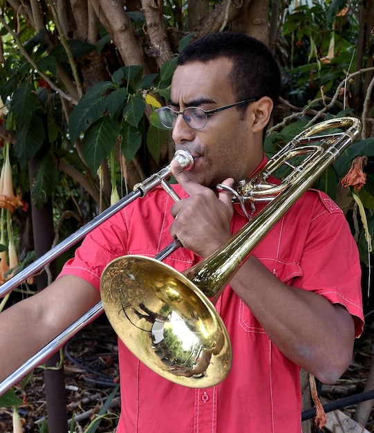 Foto ein mann spielt trompete, während er am baum steht