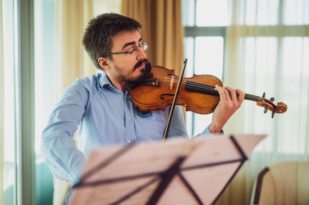 Ein Mann spielt zu Hause Geige, er übt für eine Live-Aufstellung.